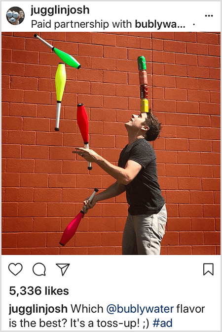 Josh Horton jonglerar klubbar som matchar färgerna på fyra Bubly-vattenburkar staplade på hans huvud. Bakgrunden är en röd tegelvägg. Bilden är en annons som Josh skapade för Bubly-vatten och publicerade i sitt Instagram-flöde med beskrivningen Vilken bublyvatten är bäst? It's A Toss Up!